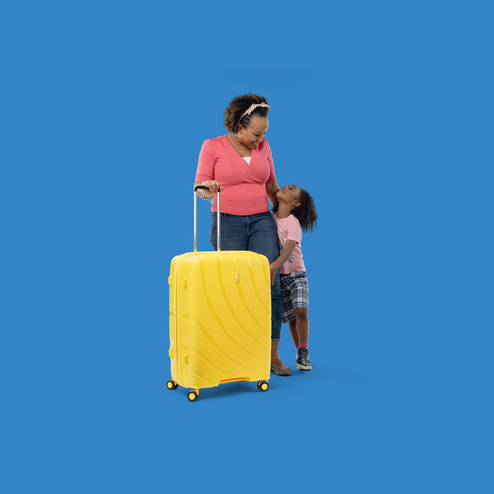 mother and son with mother holding extended handle of sunshine yellow luggage