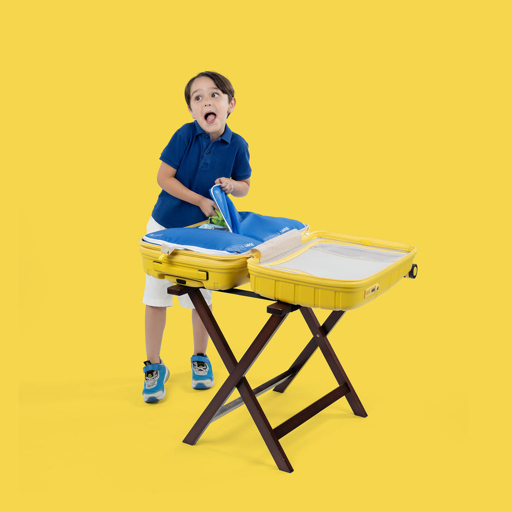boy standing next to atlantic yellow hardside spinner open putting something inside a packing cube