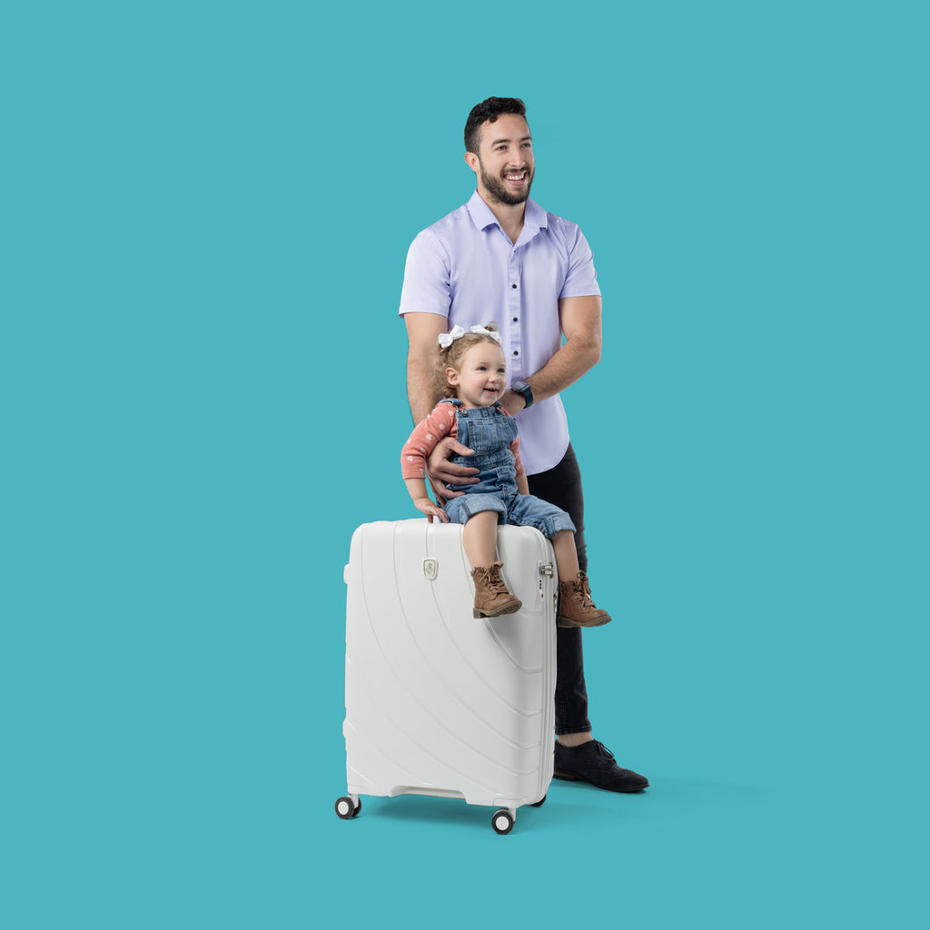 father and daughter with daughter sitting on shell white luggage